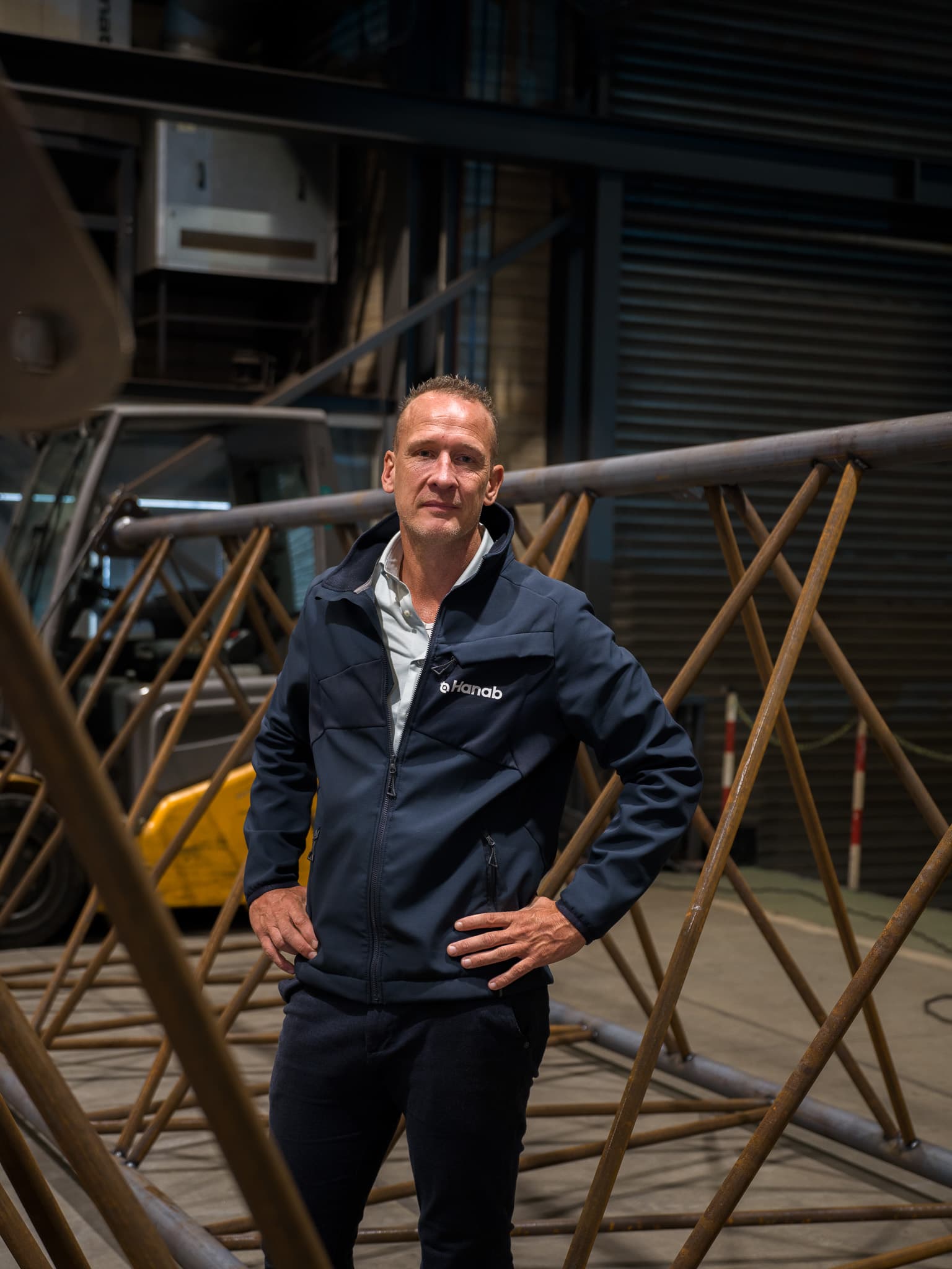 Portret van Hanab-medewerker tussen stalen vakwerkconstructies in de productiehal