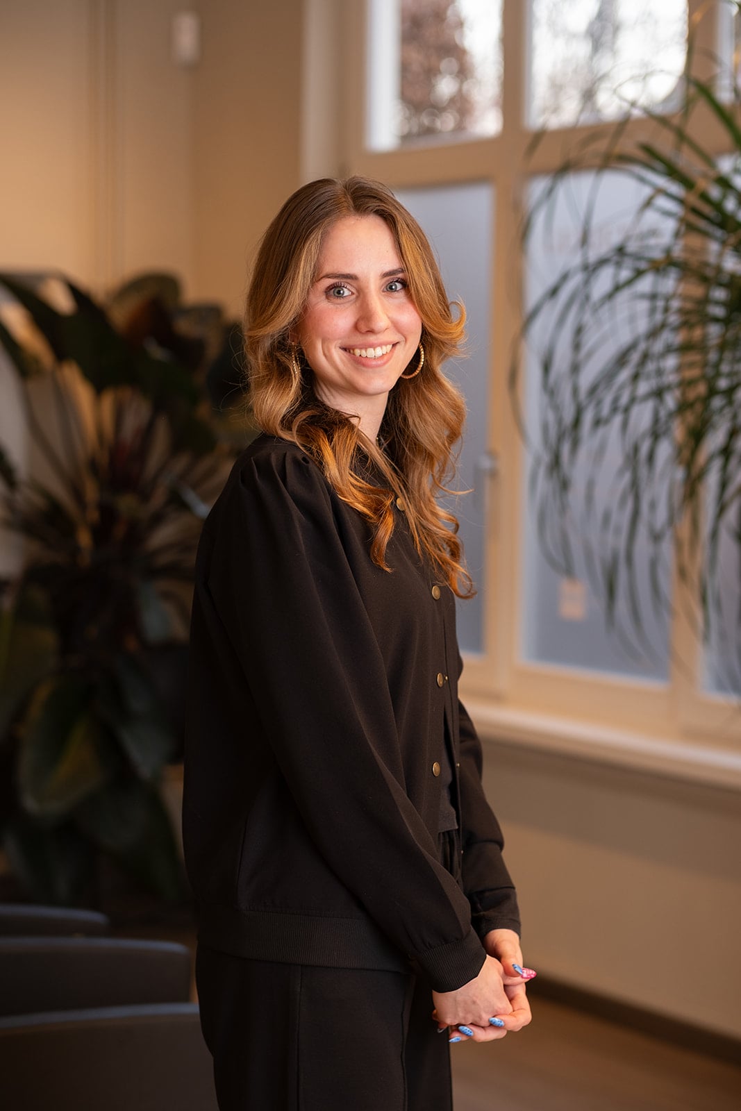 Portret blonde vrouw over schouder kijkend in zwarte kleding - headshot fotograaf regio Utrecht