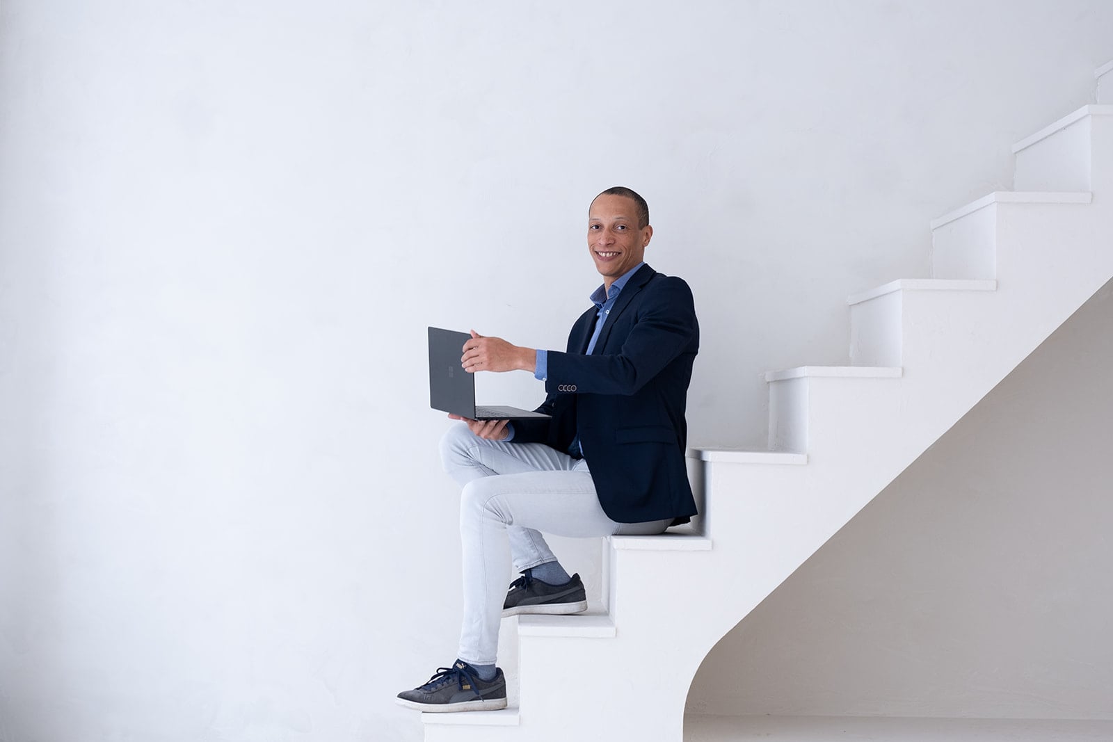 Glimlachende professional met laptop zittend op kantoor trap