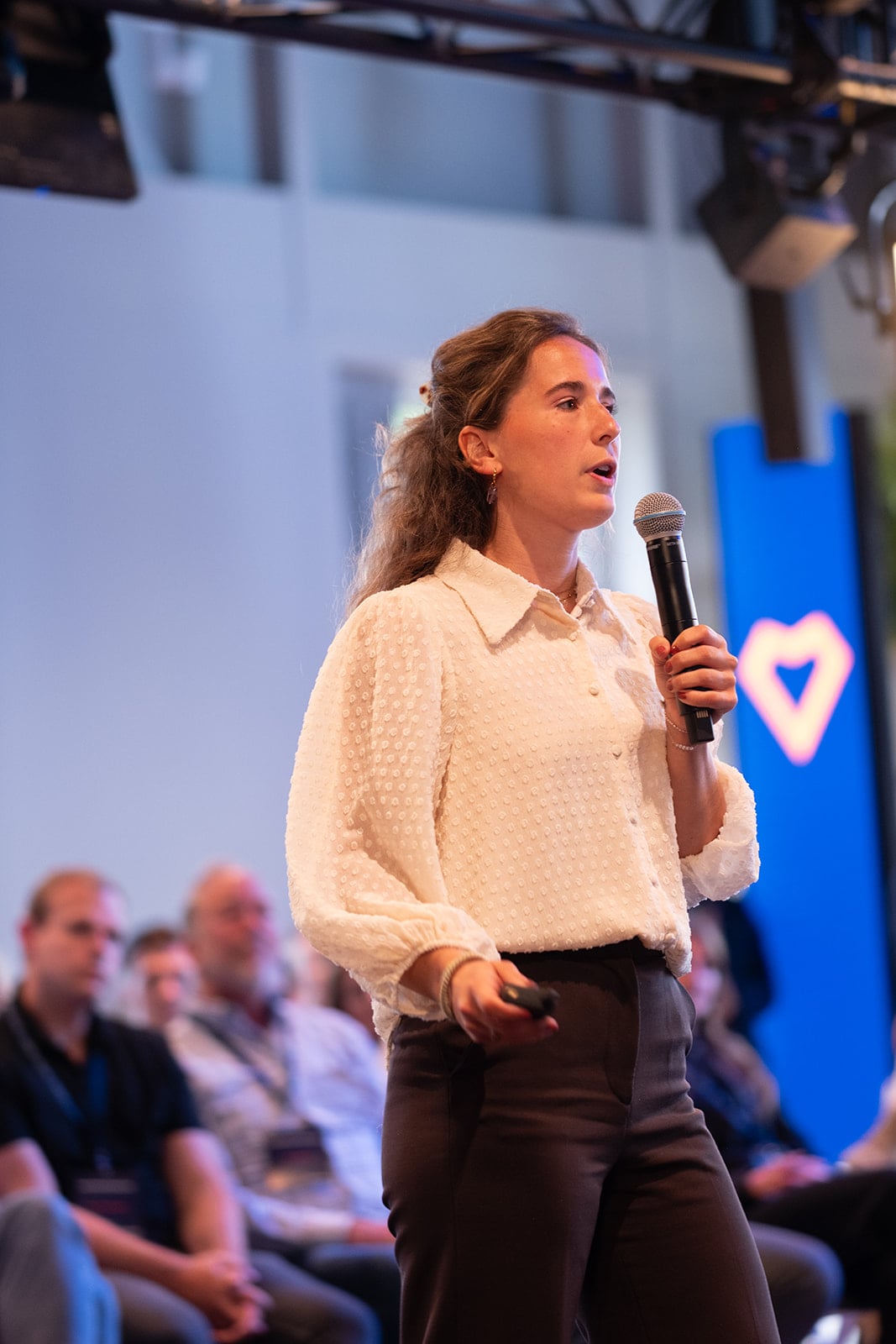 Vrouwelijke keynote speaker met microfoon tijdens bedrijfsconferentie