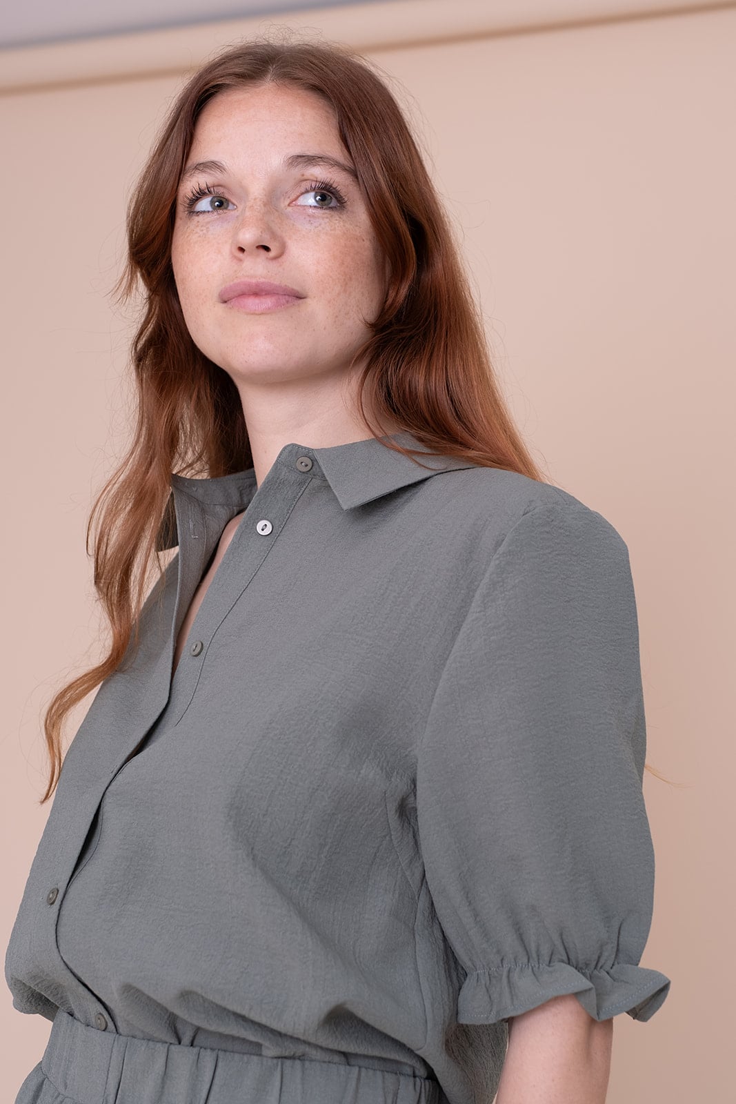 Professionele vrouw in grijze blouse kijkt omhoog - zakelijke branding fotografie Utrecht