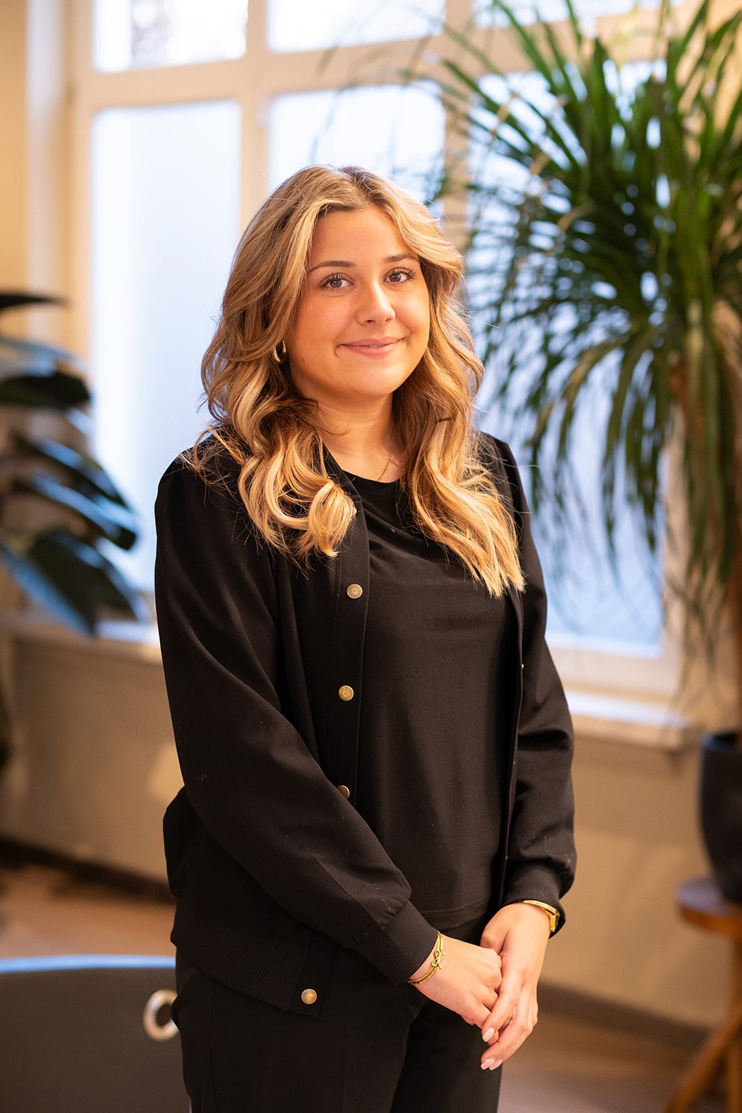 Portretfoto blonde vrouw glimlachend in zwarte cardigan - LinkedIn headshot fotograaf Utrecht