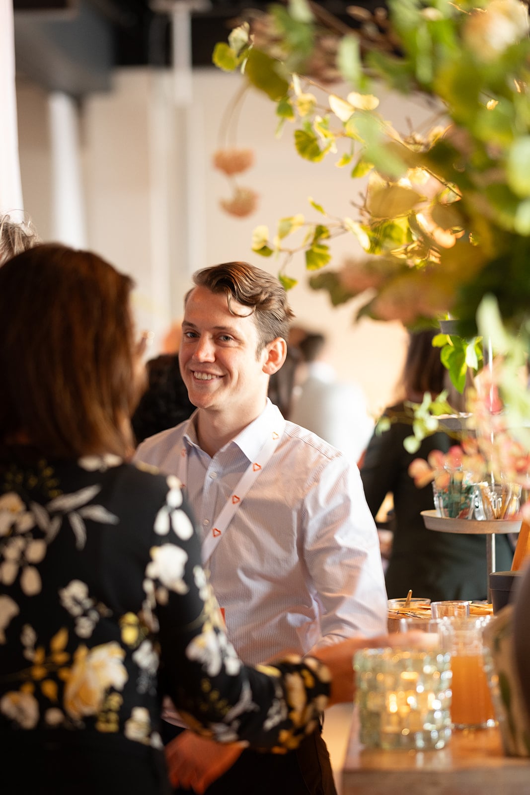 Lachende man in gesprek tijdens bedrijfsevenement met groene planten decoratie