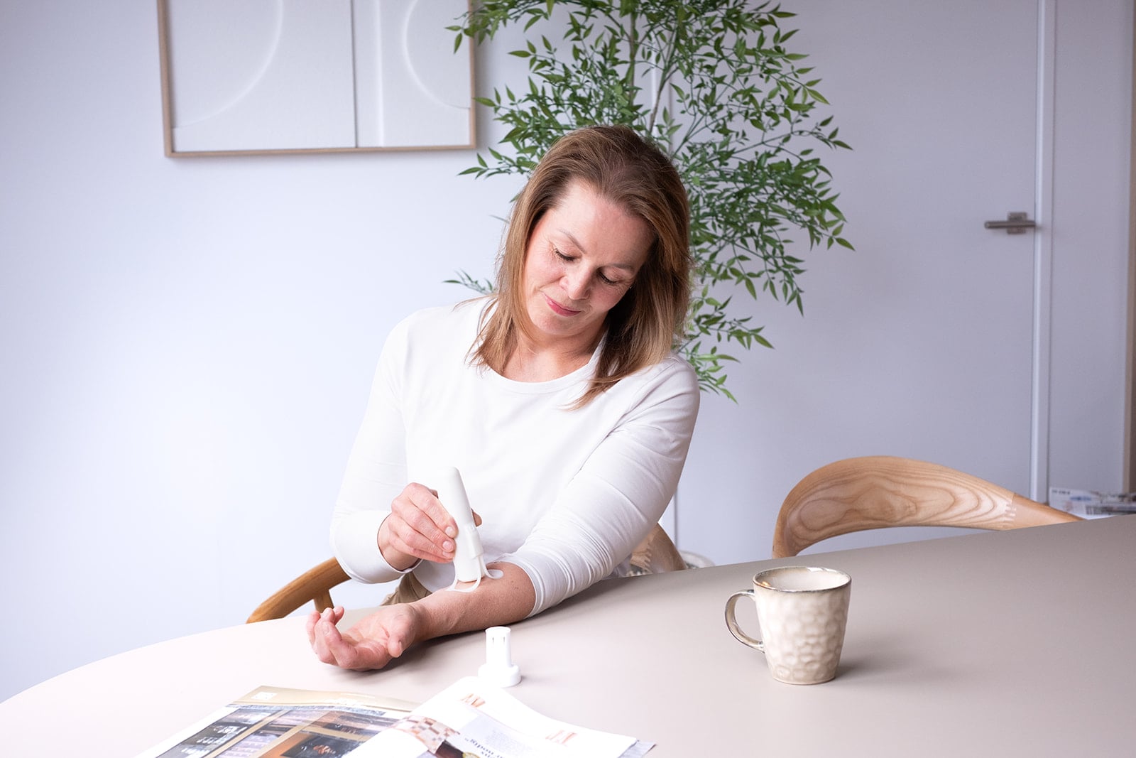 Vrouw gebruikt handcrème aan keukentafel - huiselijke branding fotografie Utrecht