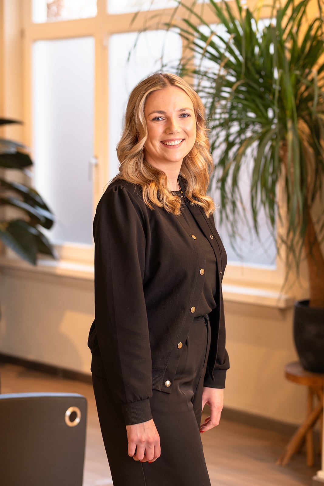 Zakelijke headshot lachende blonde vrouw in zwart jasje - professionele portretfotografie Utrecht