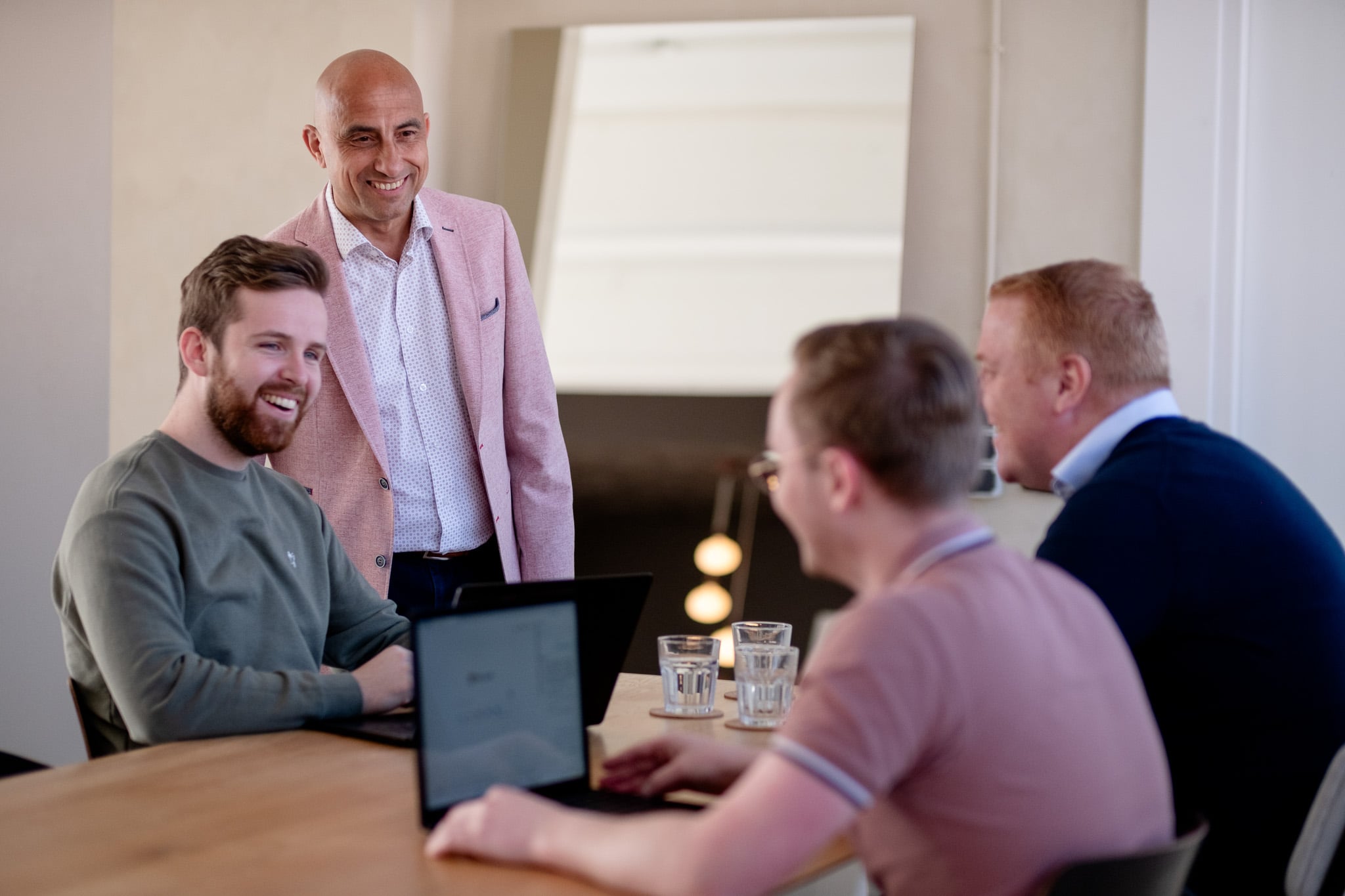 Staande zakenman in roze colbert leidt team meeting professionele bedrijfsfotografie
