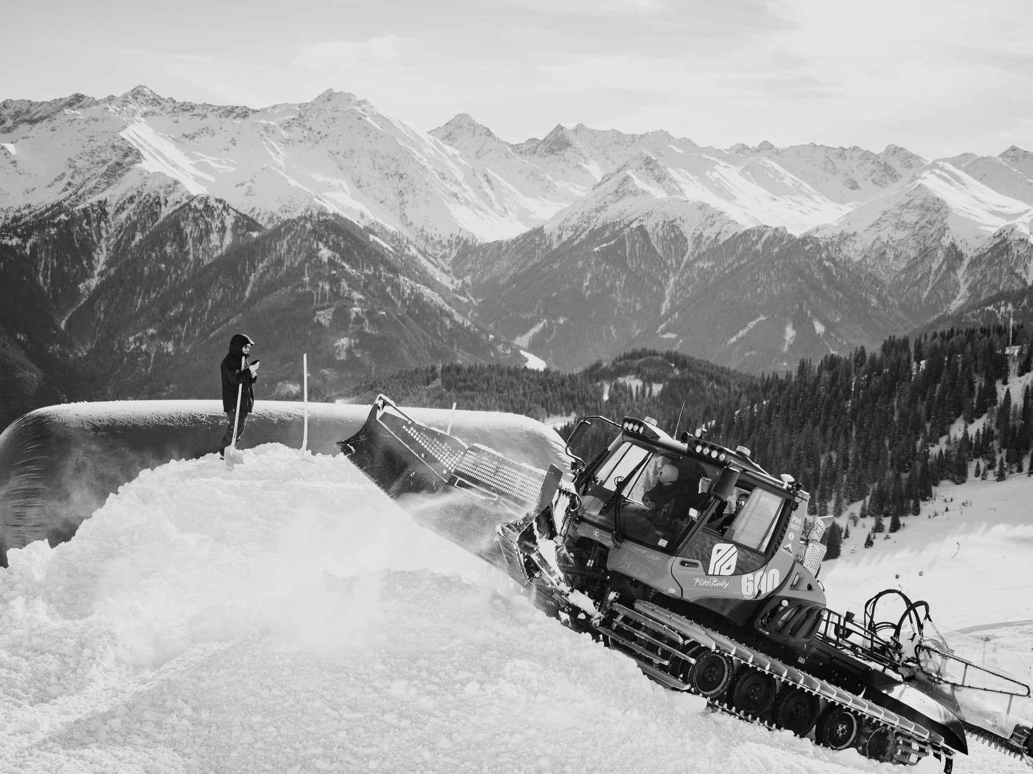 Pistenkat op steile berghelling bij bergpanorama - Alpen skiterrein onderhoud