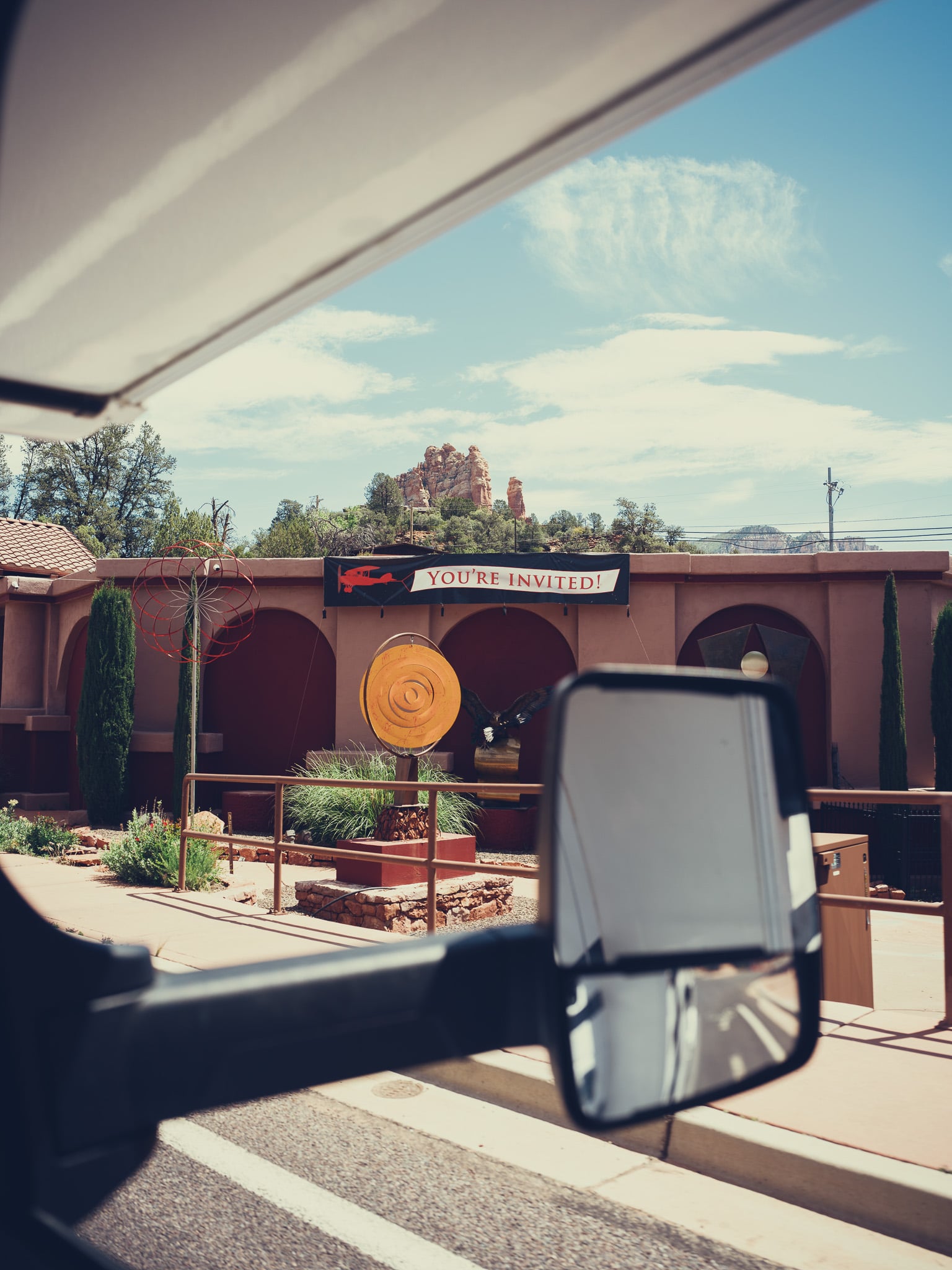 Uitzicht door een zijspiegel op een rode rotsformatie en decoratieve tuin in Sedona Arizona