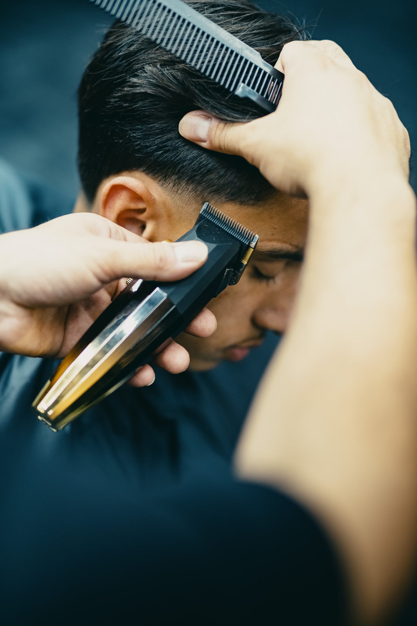 Barbier gebruikt tondeuse en kam voor precisie haarknip bij klant in moderne kapsalon