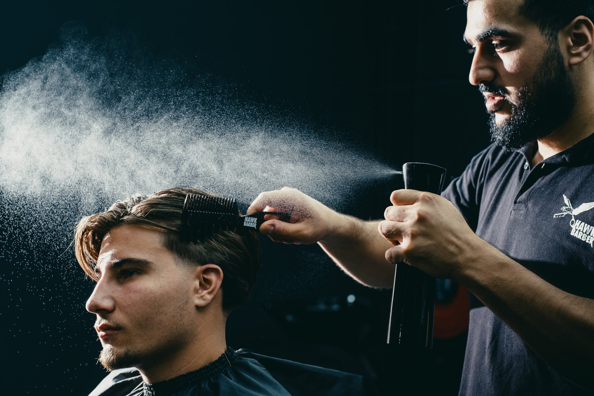 Dynamische haarspray actie tijdens styling sessie toont vakmanschap professionele barbier