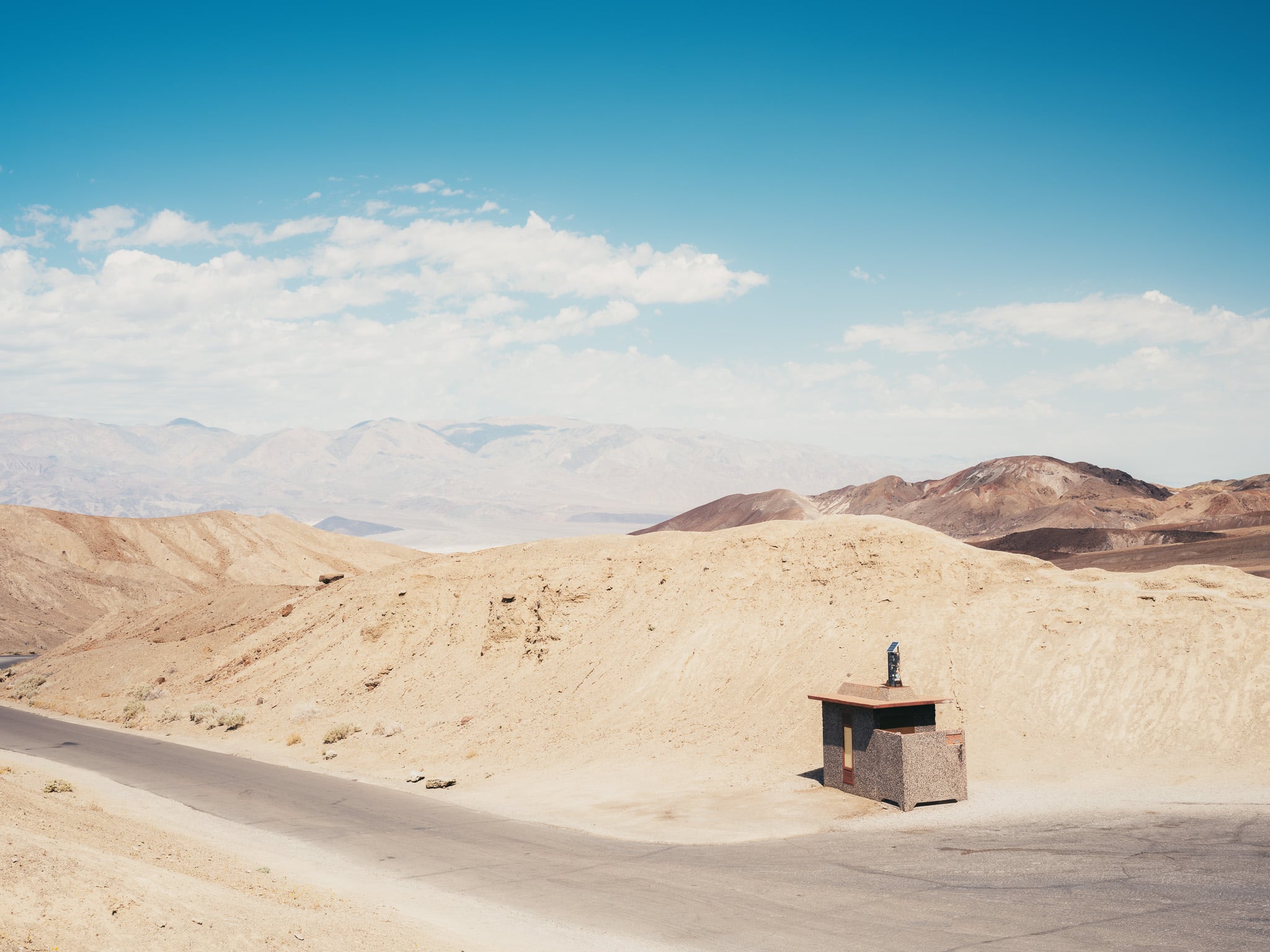 Eenzaam wachthuisje langs een woestijnweg in Death Valley met bergketen op de achtergrond