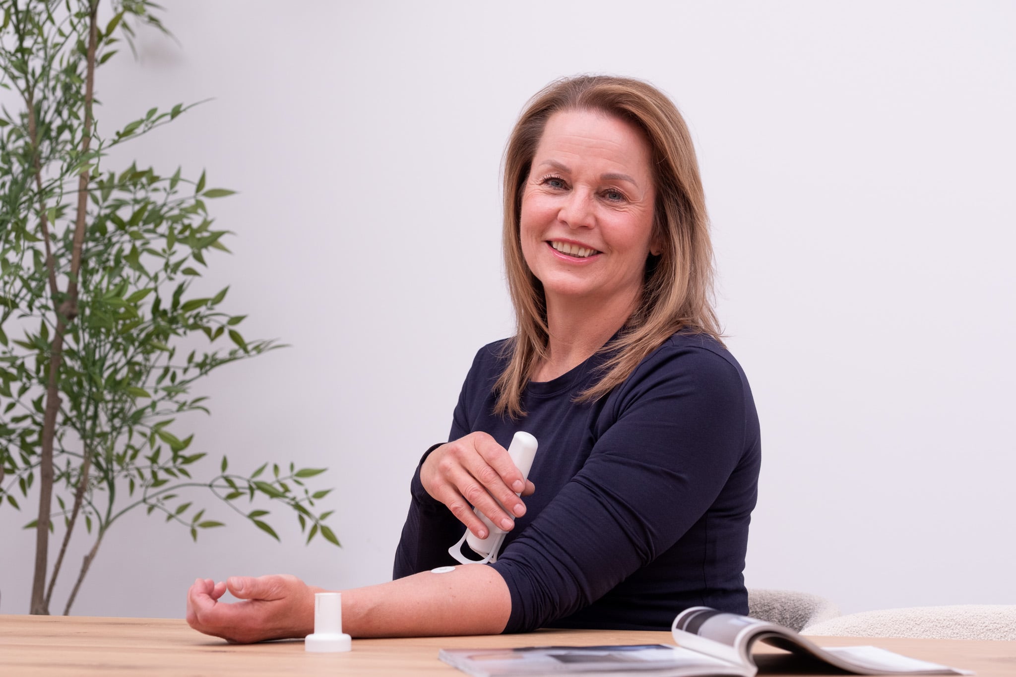 Lachende vrouw met Upatch product aan houten tafel, professionele branding fotografie Utrecht