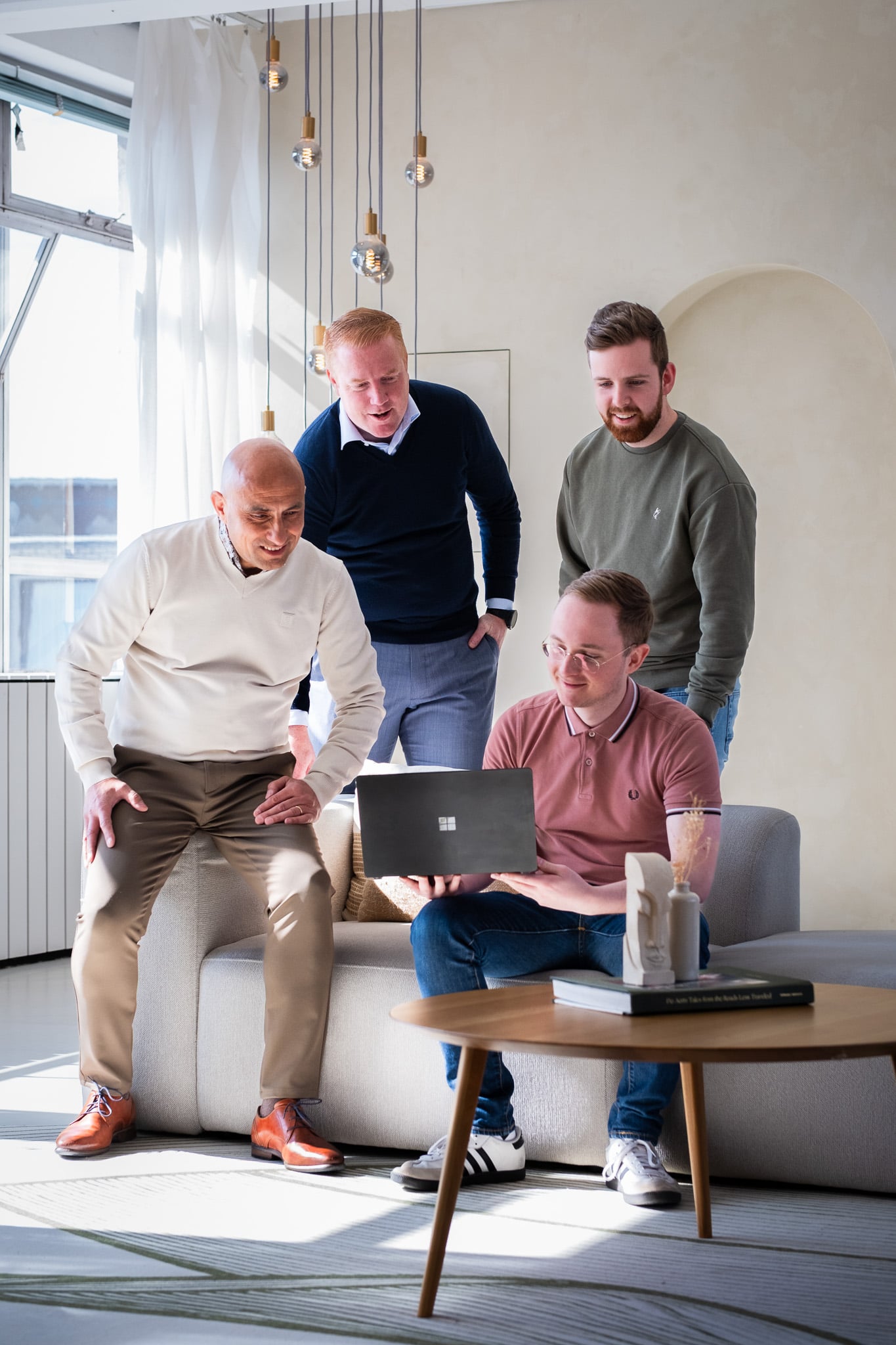 Vier collega's samenwerking rond laptop in lichte kantoorruimte teamfotografie Rotterdam