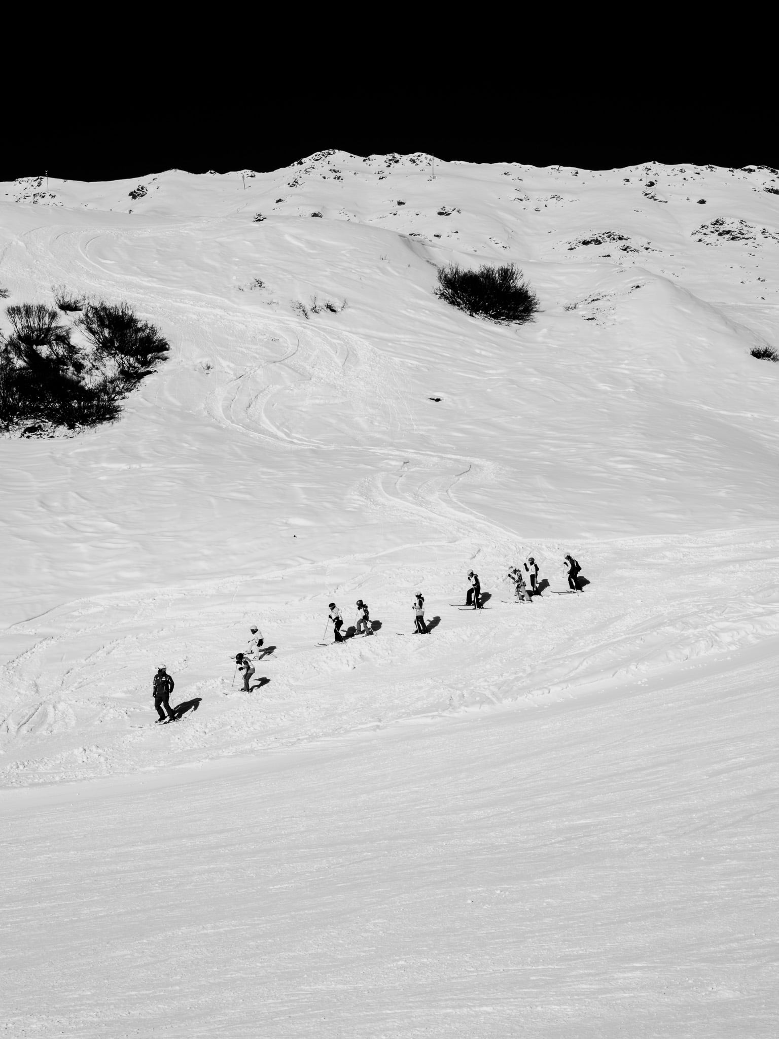 Rij skiërs daalt af door wit berglandschap - groep wintersporters op skipiste