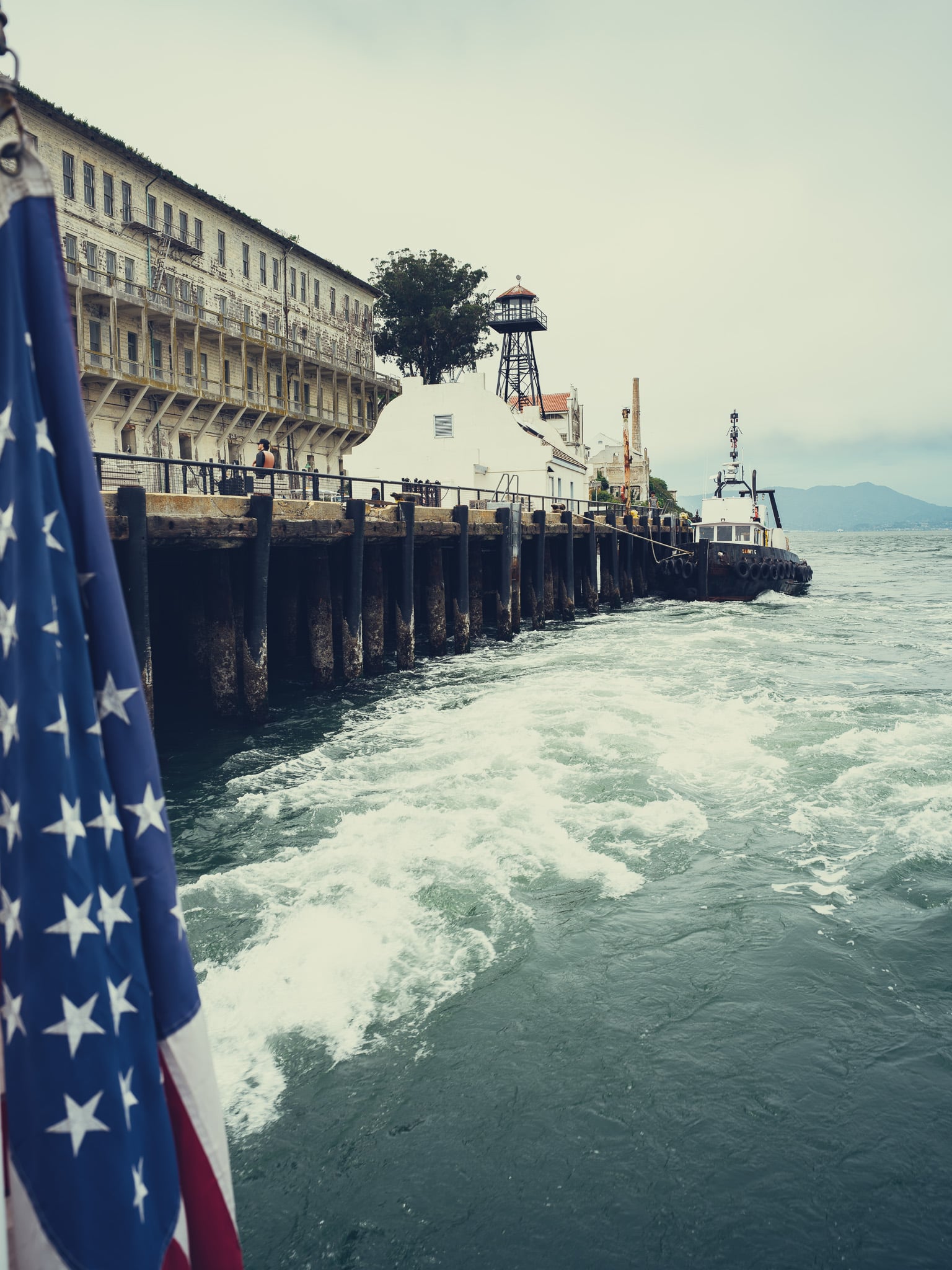 Amerikaanse vlag en gevangenisgebouw van Alcatraz gezien vanaf een boot in de baai van San Francisco
