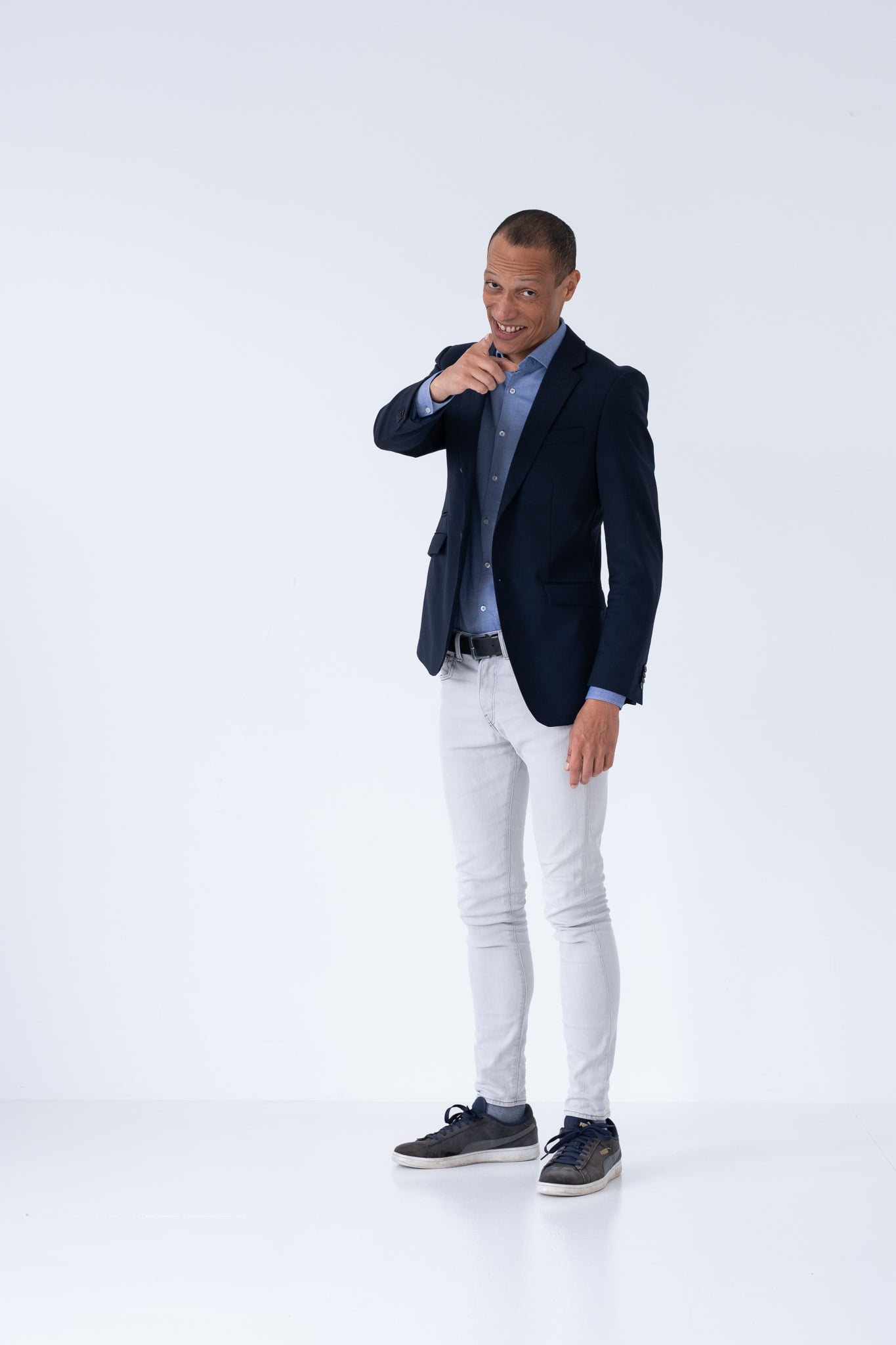 Lachende professional in casual business outfit wijzend naar camera op witte achtergrond