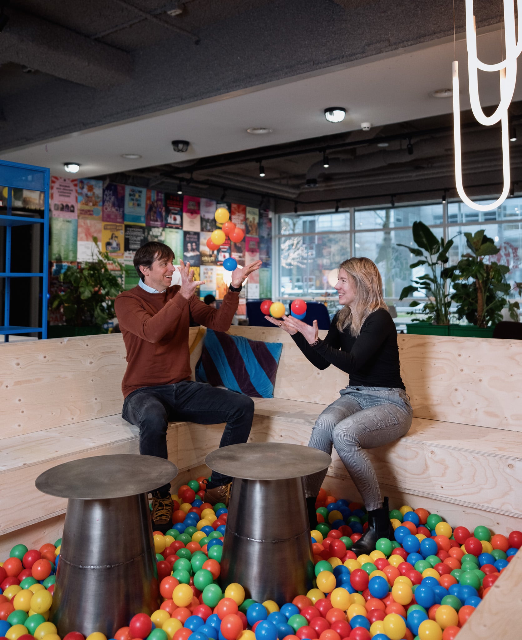 Bedrijfsfotografie collega's gooien ballen samen speelse werksfeer moderne kantooromgeving