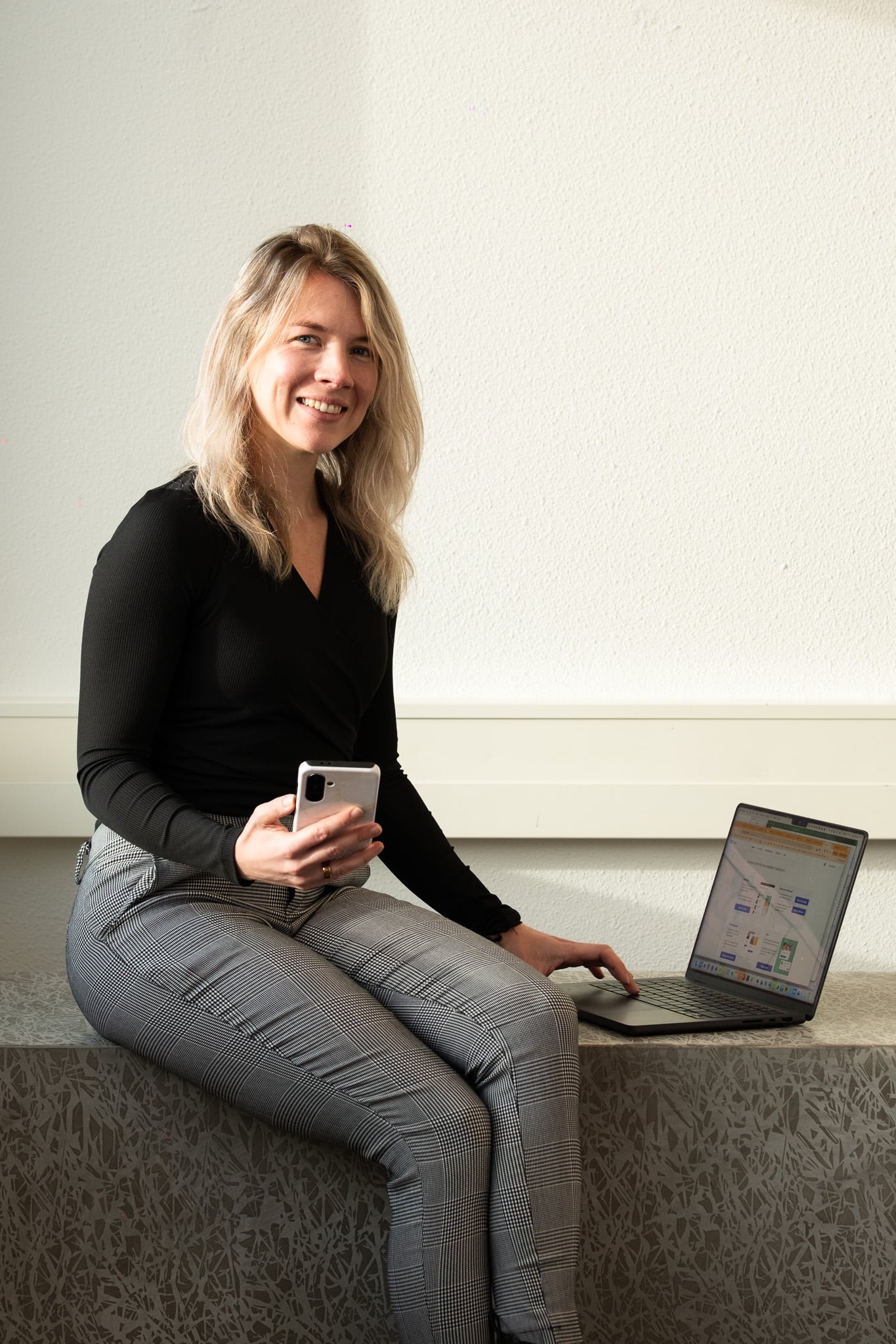 Professionele portretfotografie blonde vrouw zwarte blouse laptop smartphone kantoor Utrecht