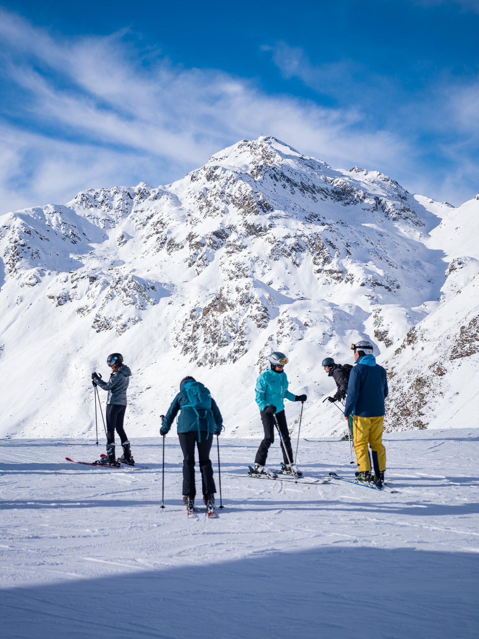 Groep skiërs op plateau met majesteiteuze bergtoppen - Alpine groepsfotografie