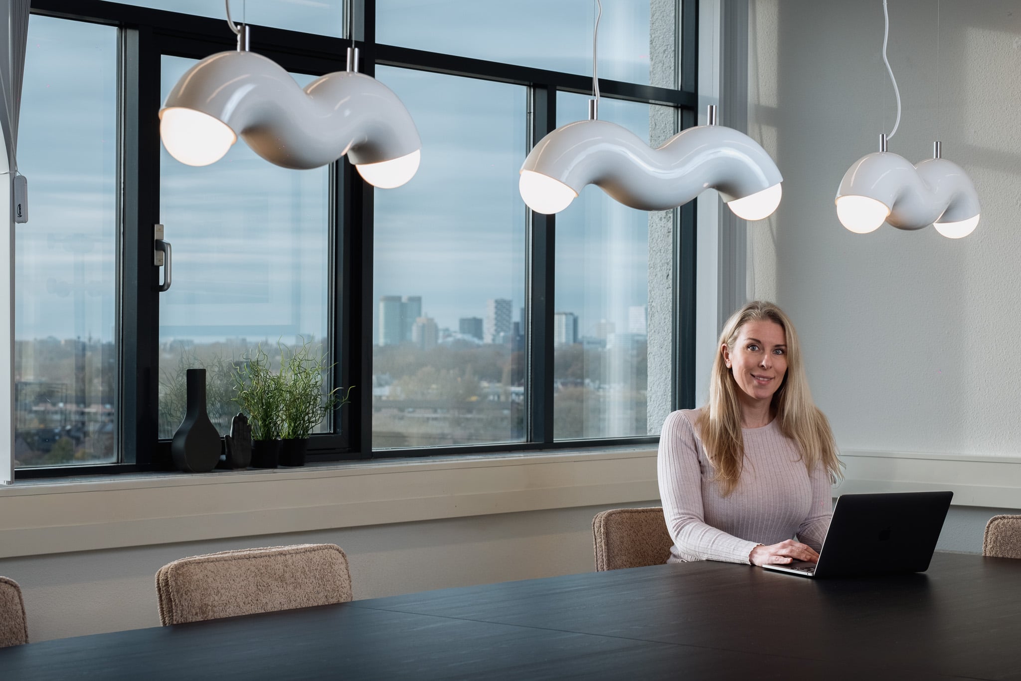 Zakelijke portretfotografie blonde vrouw vergaderruim moderne lampen stadsuitzicht Utrecht