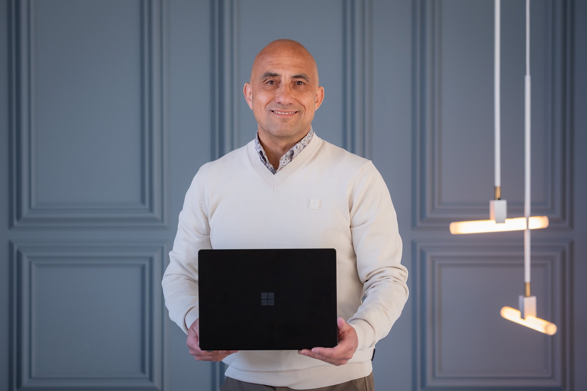 Kale zakenman in witte trui toont laptop lachend corporate portret Rotterdam
