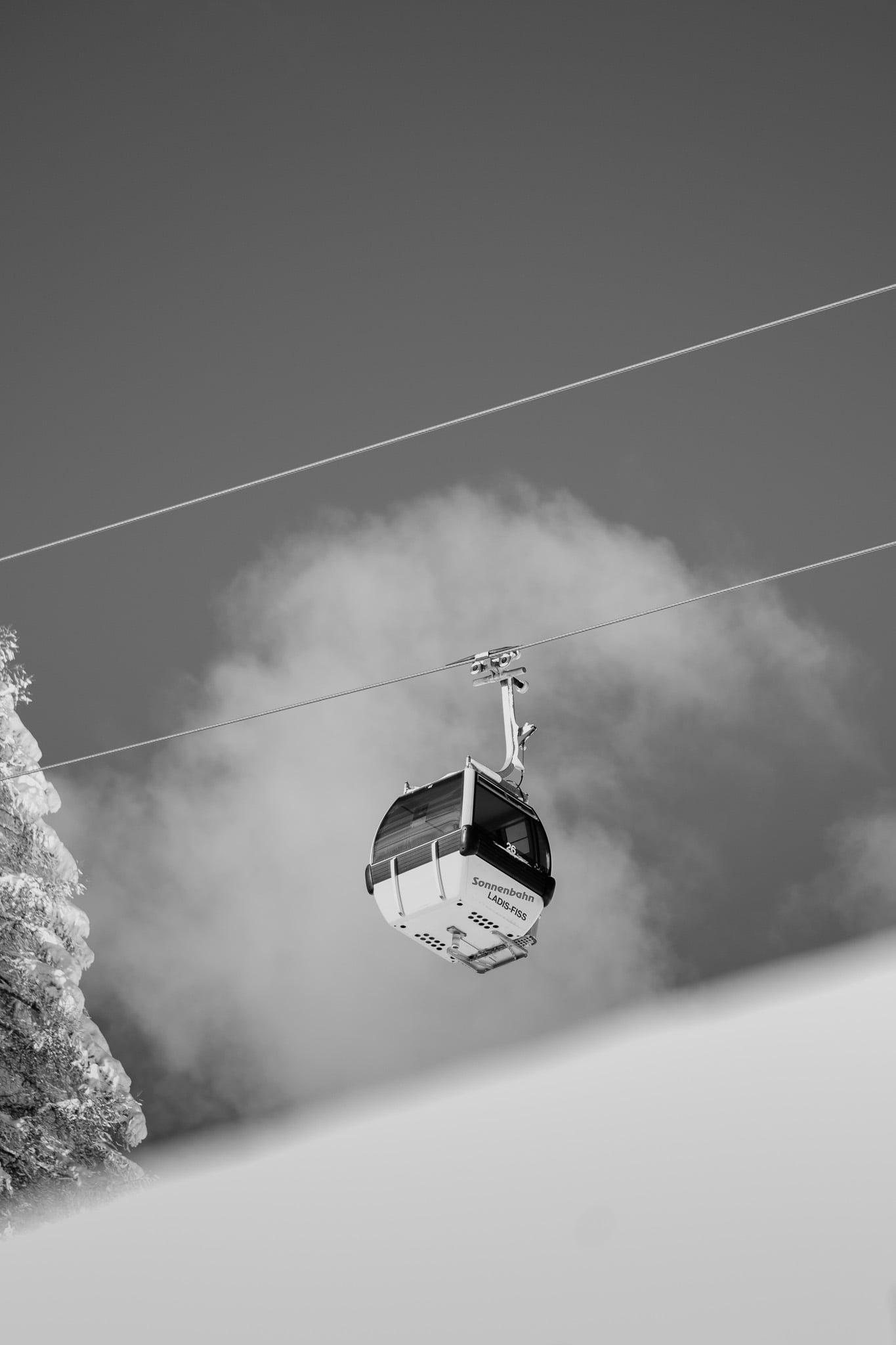 Zwart-wit stoeltjeslift cabine tegen bewolkte hemel - minimalistisch lift ontwerp