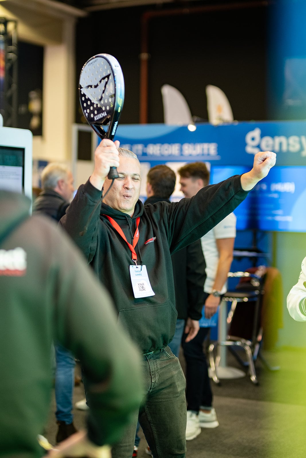 Juichende man met padel racket viert overwinning op sportieve tech beurs activiteit