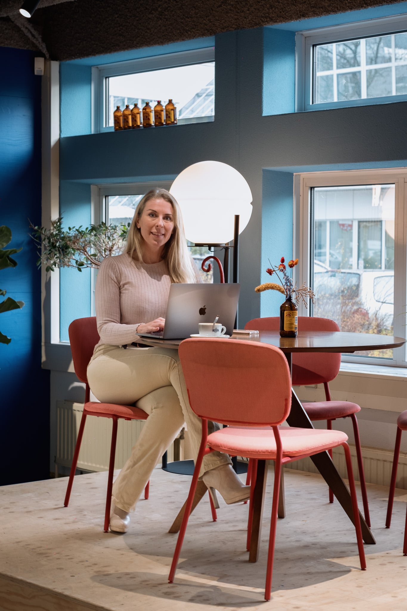 Bedrijfsfotografie vrouw beige trui moderne werkplek kleurrijke stoelen natuurlijk licht