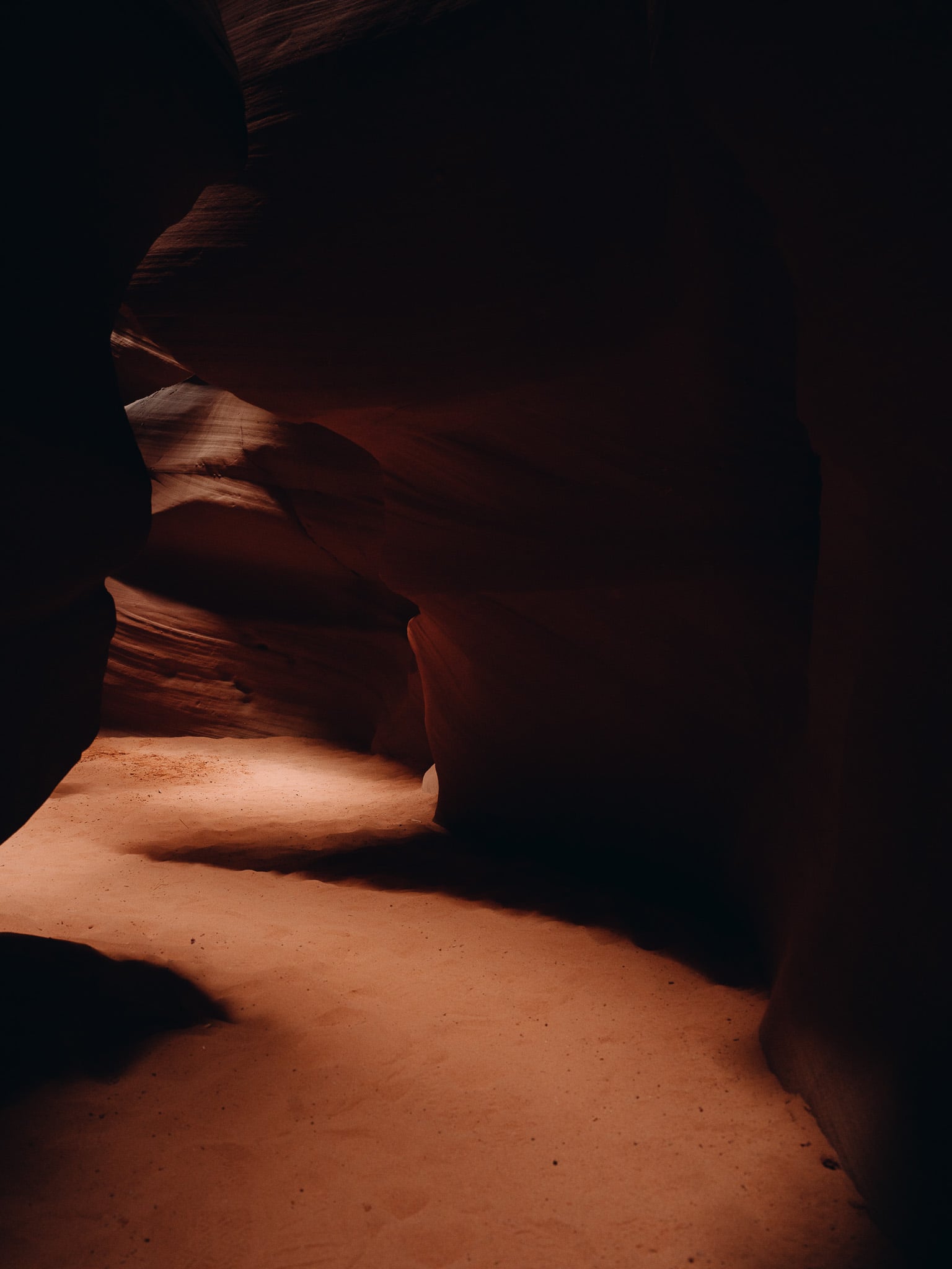 Zonlicht valt door een spleet en verlicht de gladde zandstenen vloer van een slot canyon