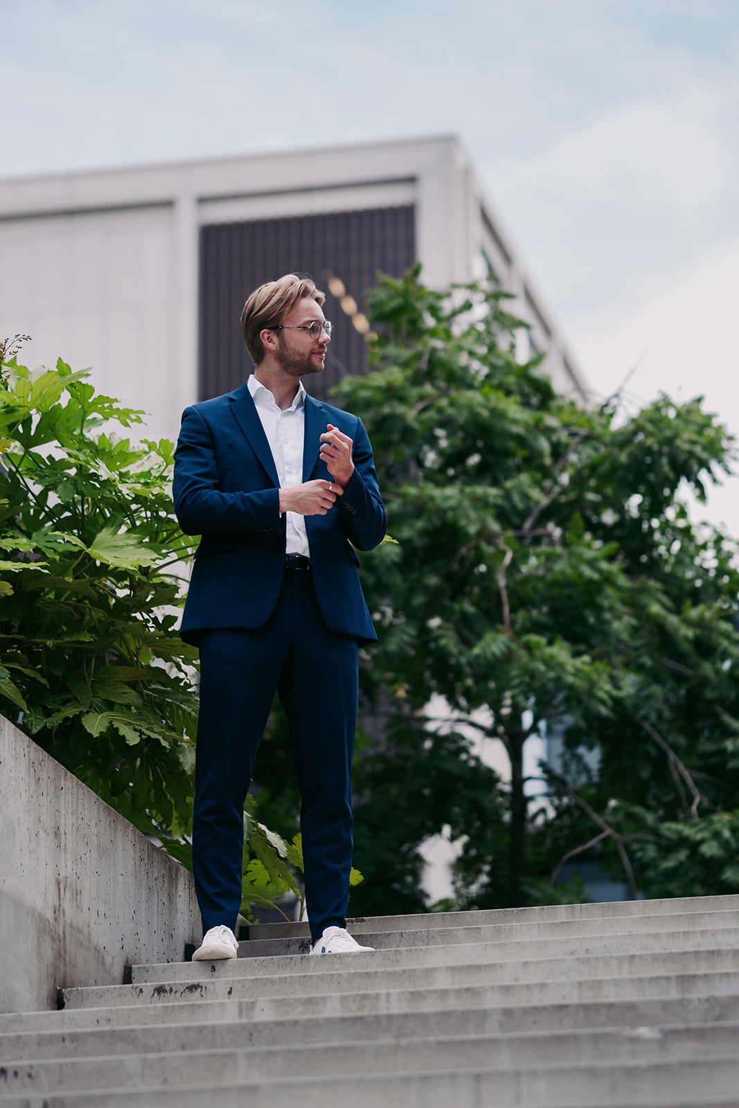 Man blauw pak zonnebril manchetten dichtmaken betonnen trap professionele bedrijfsfotografie Utrecht