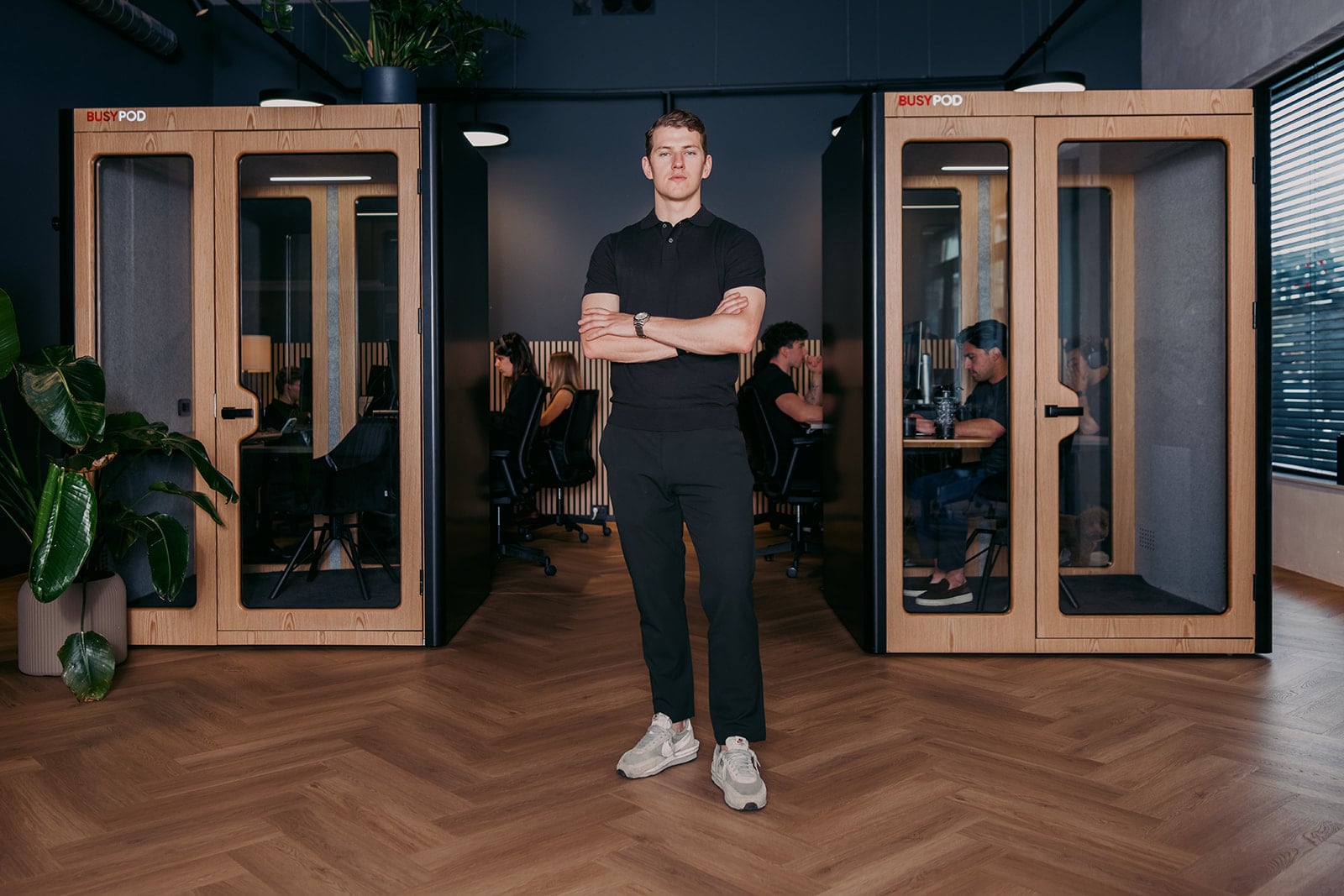 Zakelijk portret man gekruiste armen zwart poloshirt moderne kantooromgeving Utrecht bedrijfsfotografie